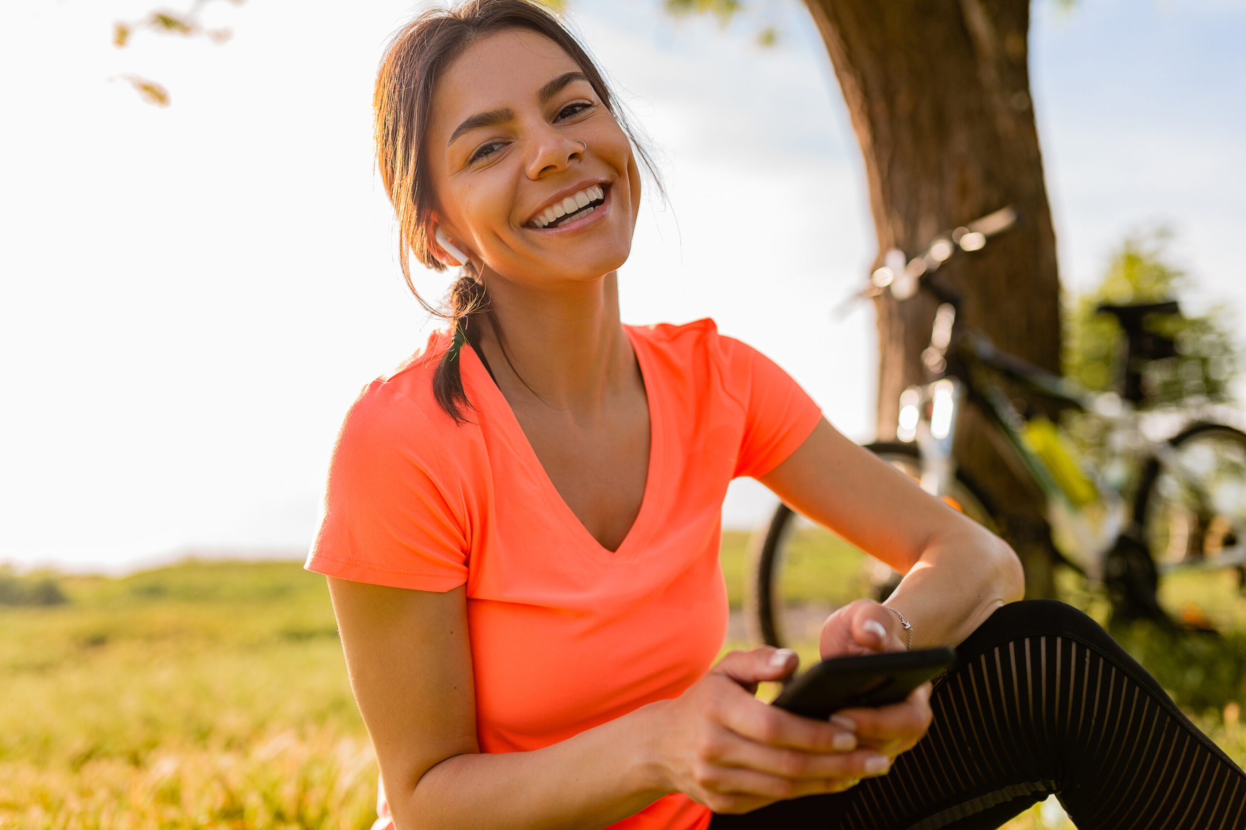 Lady holding phone with bike in park